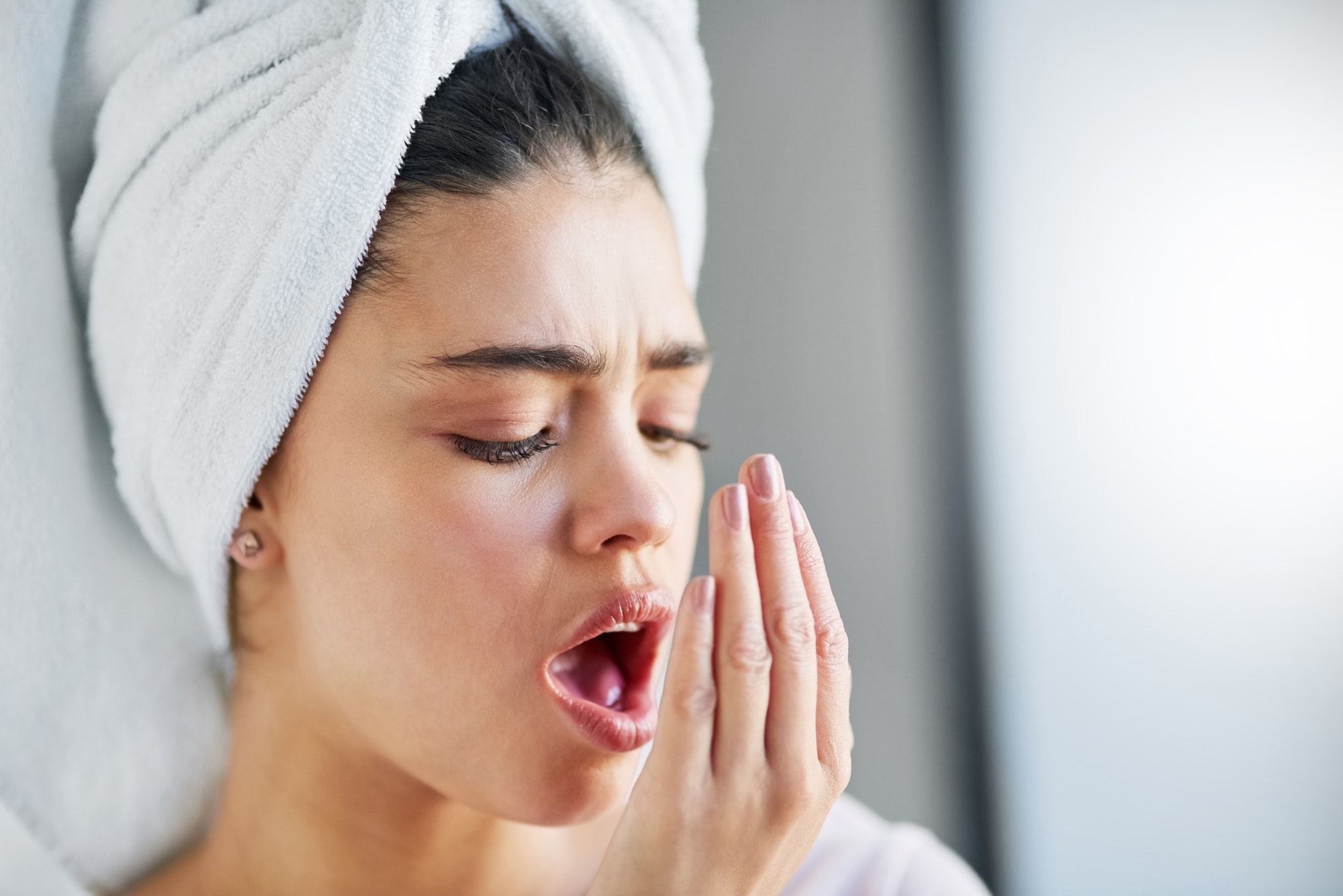 Check up on your oral hygiene. Shot of a beautiful young woman checking her breath at home.
