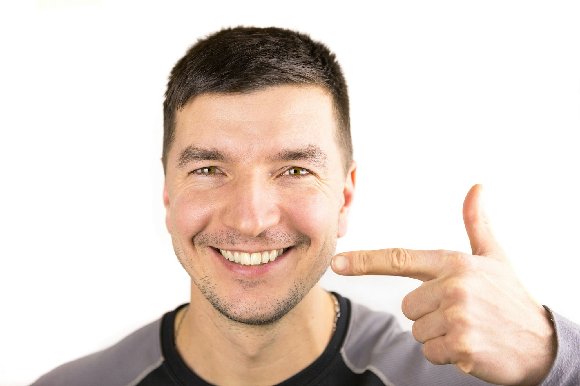 Beautiful male snow-white smile and lips of Caucasian appearance close-up. Points finger at the teet